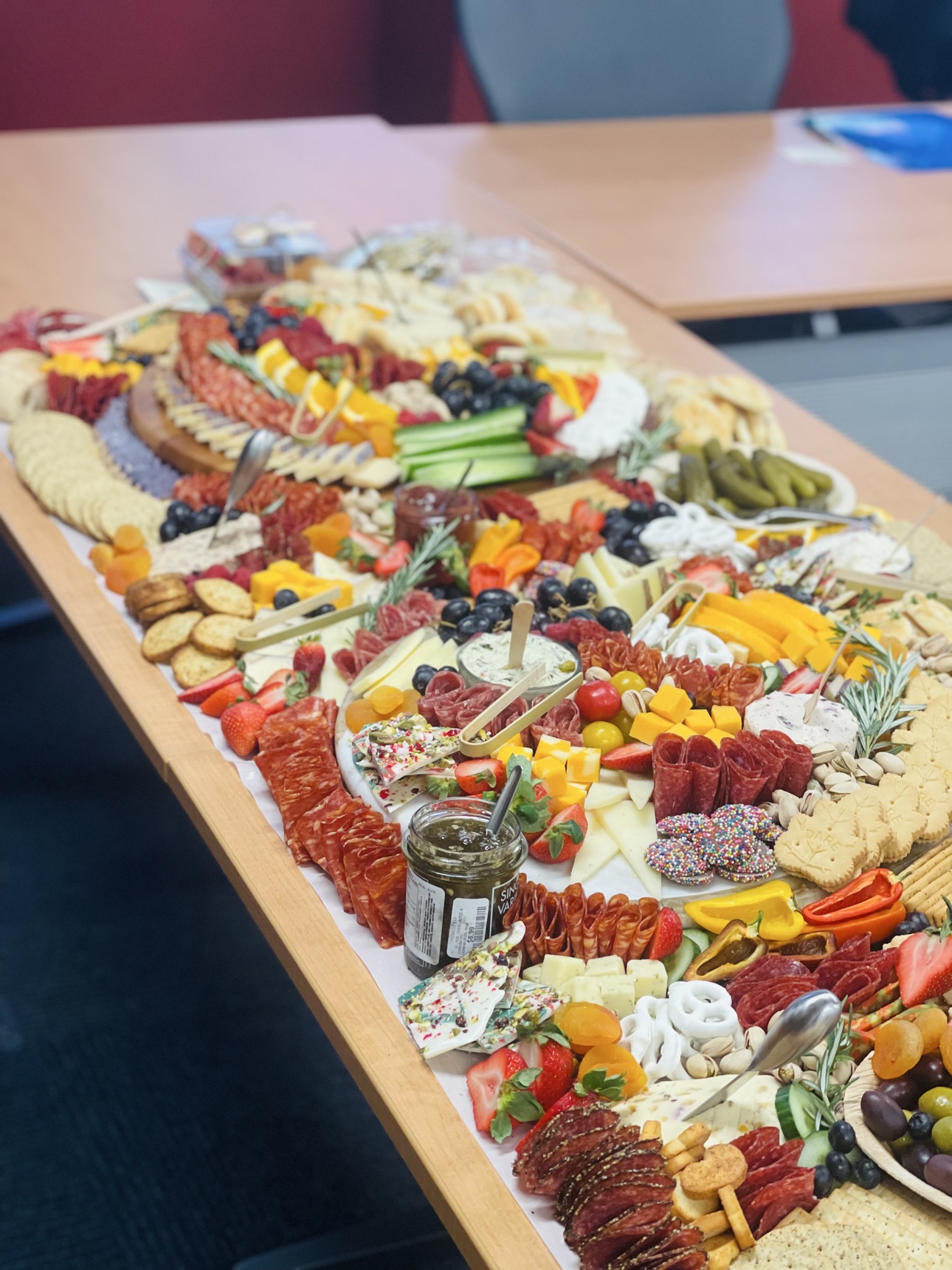 A long grazing table runner styled with meats, cheeses, fruit and crackers