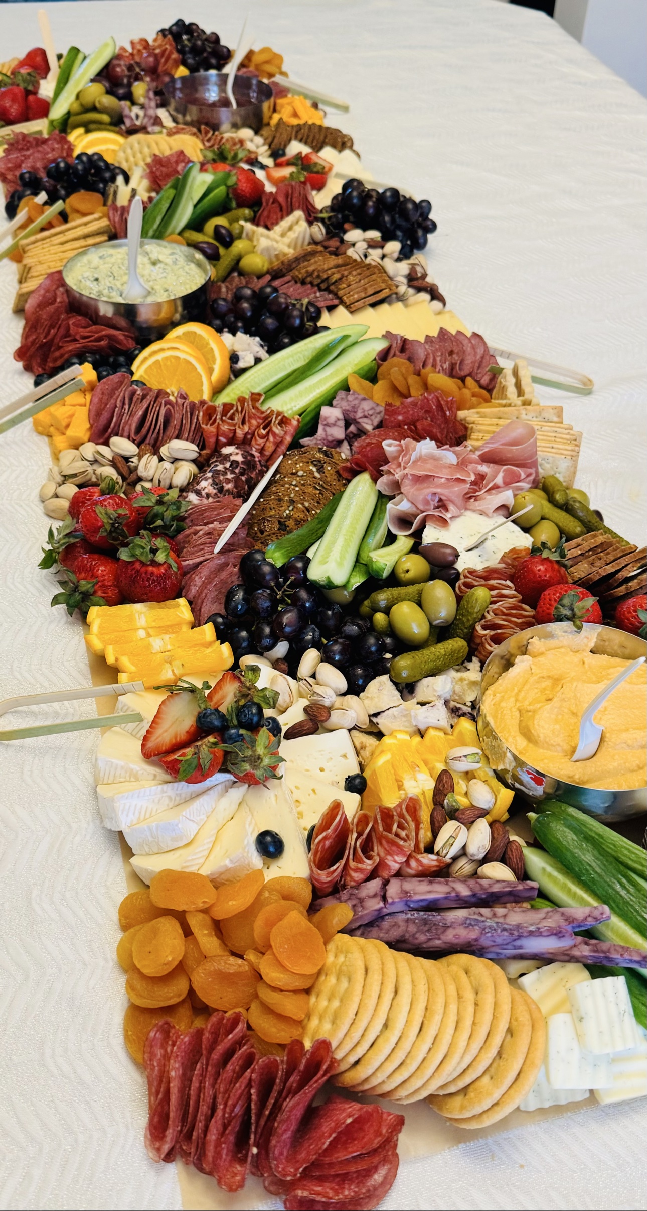 Grazing table spread with meats, cheeses, dips, fruit and crackers